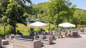 Outdoor seating with umbrellas, a paved patio, and a view of a residential area. - Bungalow im Campingpark (Waxweiler)