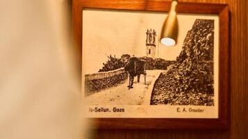 A framed photograph of a landscape with a cow and a building, mounted on a wooden wall.