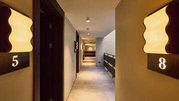 A hotel hallway with doors numbered 5 and 8, a carpeted floor, and a railing on the right.