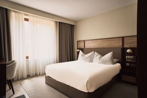 Une chambre d’hôtel avec un grand lit, un bureau et une chaise.