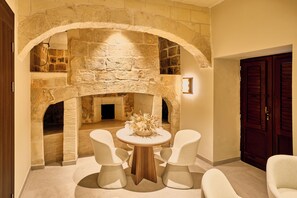 A stone fireplace with a round table and chairs in front. - Quaint Signature Hotel San Lawrenz (San Lawrenz)