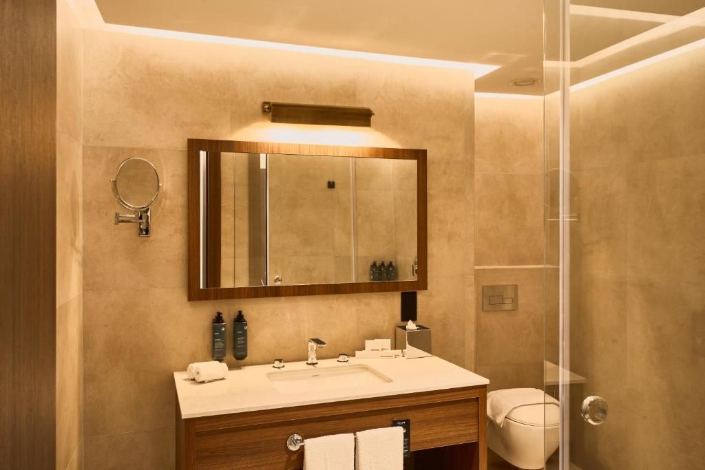 Un baño moderno con un espejo grande, un lavabo y un inodoro.