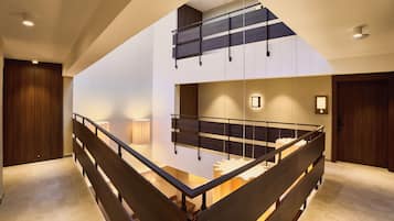 Ein modernes Interieur mit einer Holztreppe, einer erhöhten Galerie und Blick in den angrenzenden Raum.