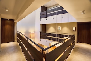 A modern interior with a wooden staircase, a mezzanine level, and a view of the adjacent room. - Quaint Signature Hotel San Lawrenz (San Lawrenz)