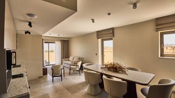 A modern hotel room with a dining area, a sofa, and a view of the desert.