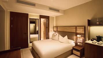Una habitación de hotel con una cama grande, mesitas de noche, un armario y un espejo.