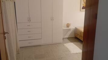 Una habitación con armario, cama, una mesita y una lámpara colgante.