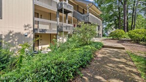 Un immeuble à plusieurs étages, doté de balcons et entouré de verdure et d’arbres.