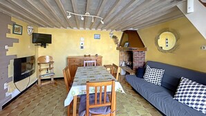 Ein gemütliches Zimmer mit Esstisch, Stühlen, einer Couch und einem Kamin.