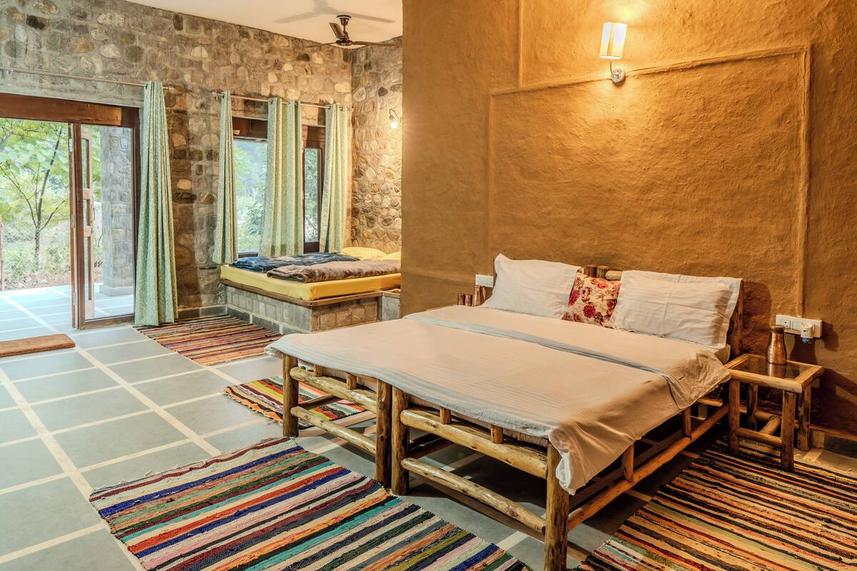 A spacious bedroom with a large bed, a stone wall, and a view of the outdoors.