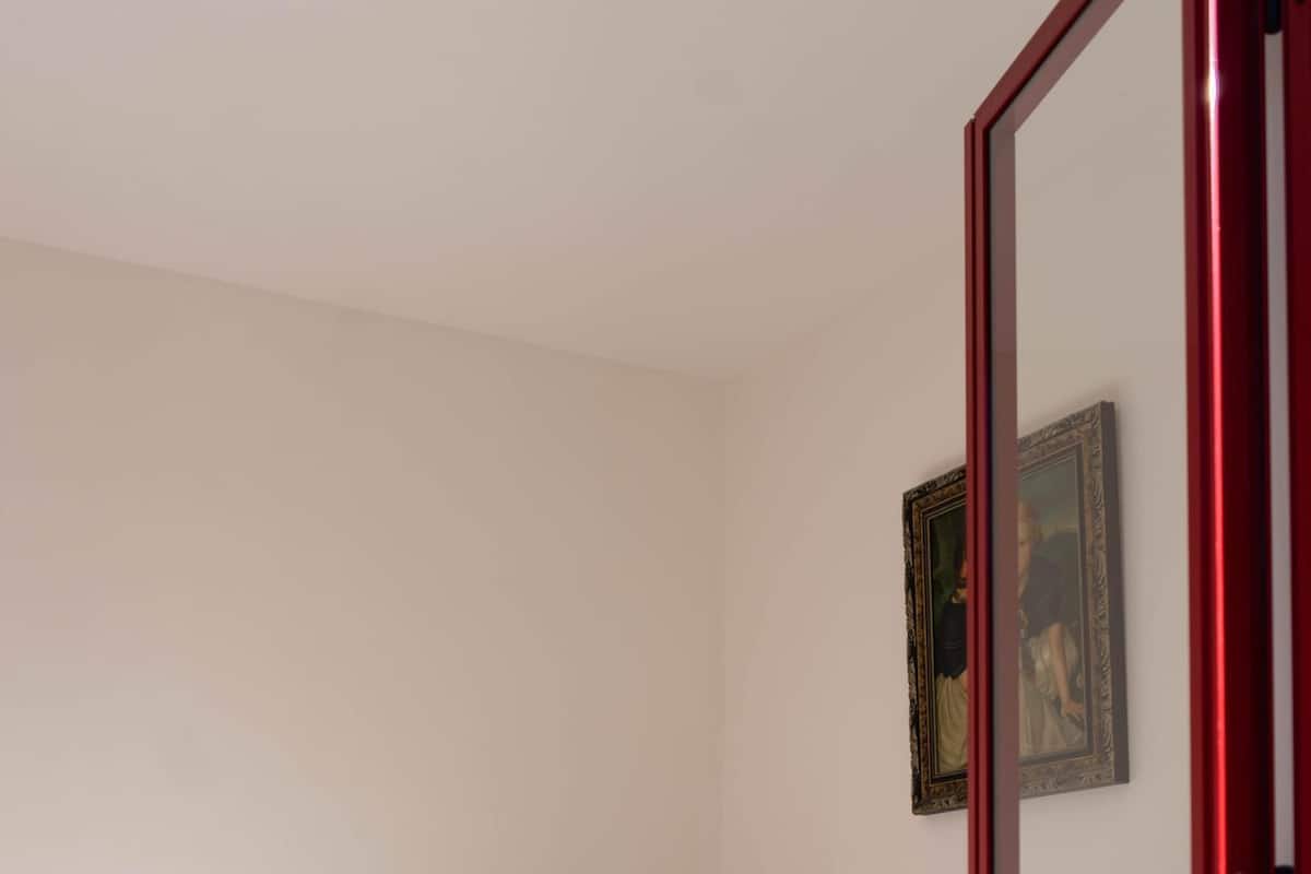 A single bed with a white mattress and a wooden headboard in a room with white walls.