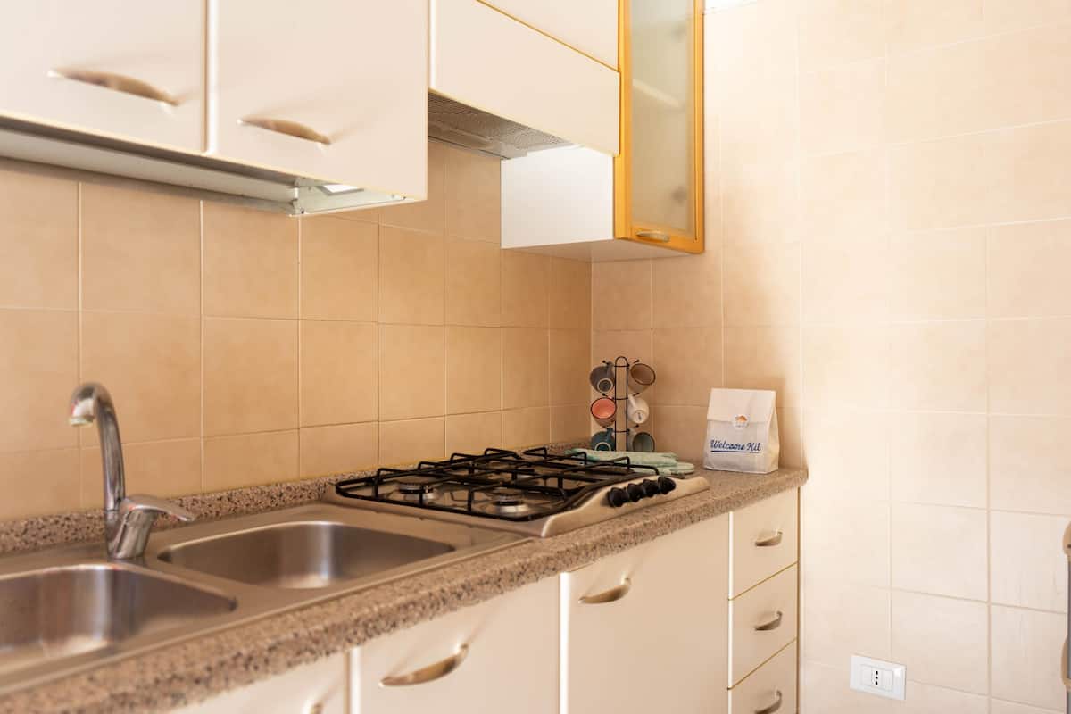 A kitchen with two sinks, a gas stove, and white cabinets.