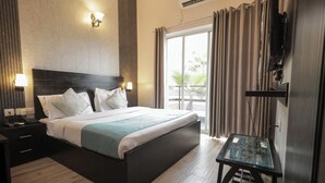 Camera d'albergo con un letto grande, lampade sui comodini, un tavolino e una TV a parete.