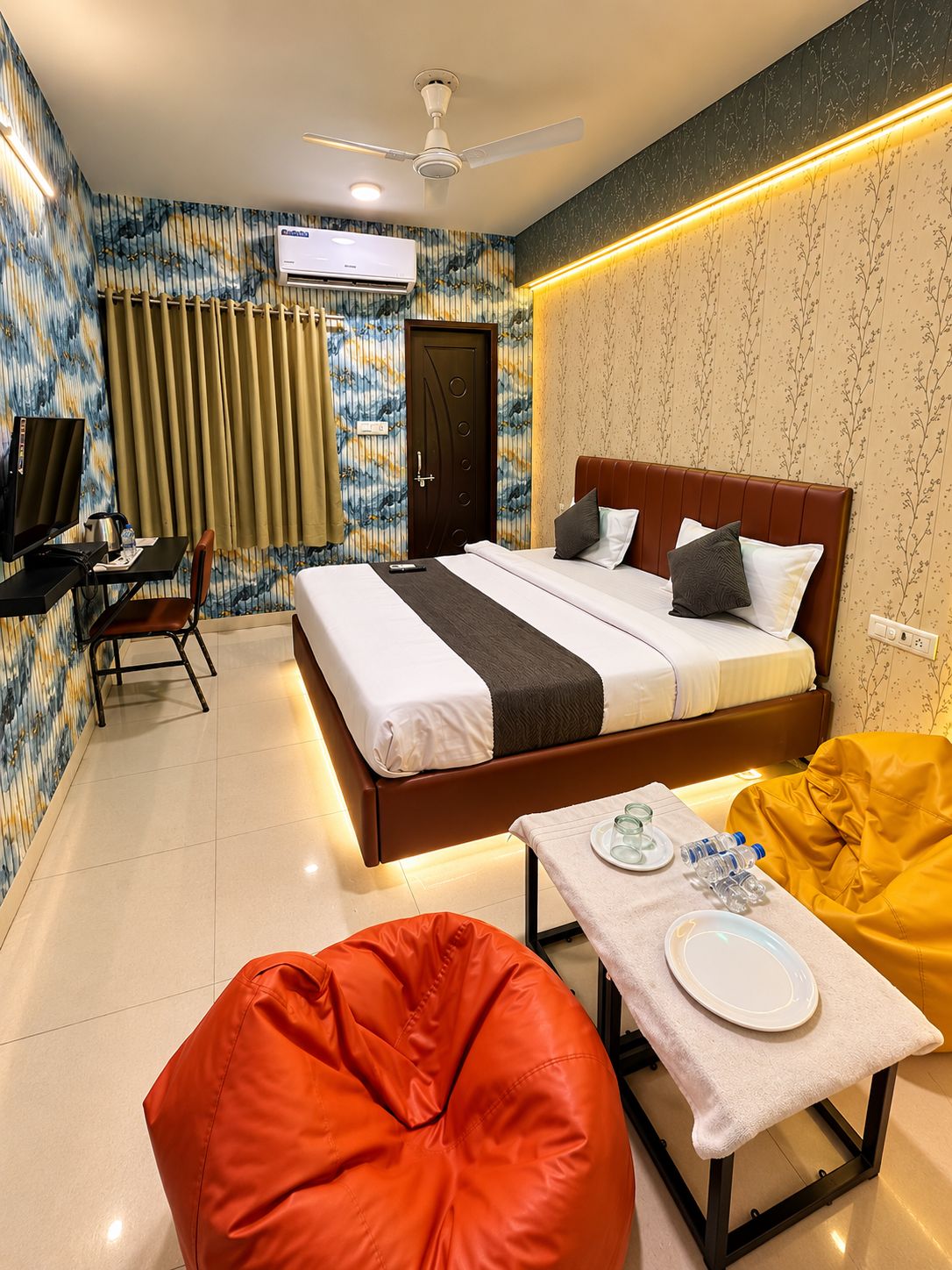 Une chambre d’hôtel avec un lit, un bureau et une chaise, un téléviseur et un fauteuil en forme de sac de haricots rouge.