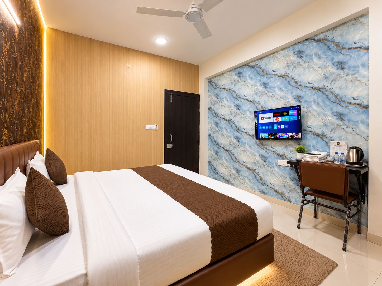 Een hotelkamer met een bed, een bureau, een televisie en een marmeren wand.