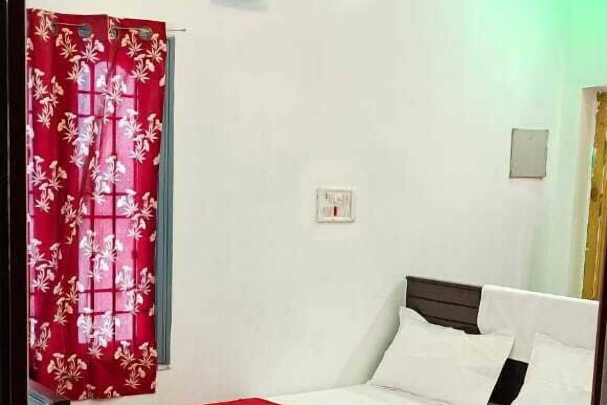 Ein Schlafzimmer mit einem Bett, einer roten Bettdecke, einer Klimaanlage und einem Deckenventilator.