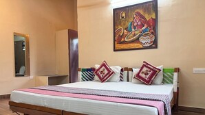 Ein ordentlich bezogenes Bett mit Holzbettgestell, ein Spiegel an der Wand und ein Gemälde, das eine traditionelle Szene zeigt.