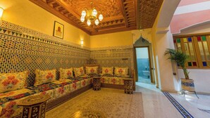 A traditional Moroccan interior with a patterned sofa, intricate ceiling, and a chandelier. - Riad Brothers (Marrakech)