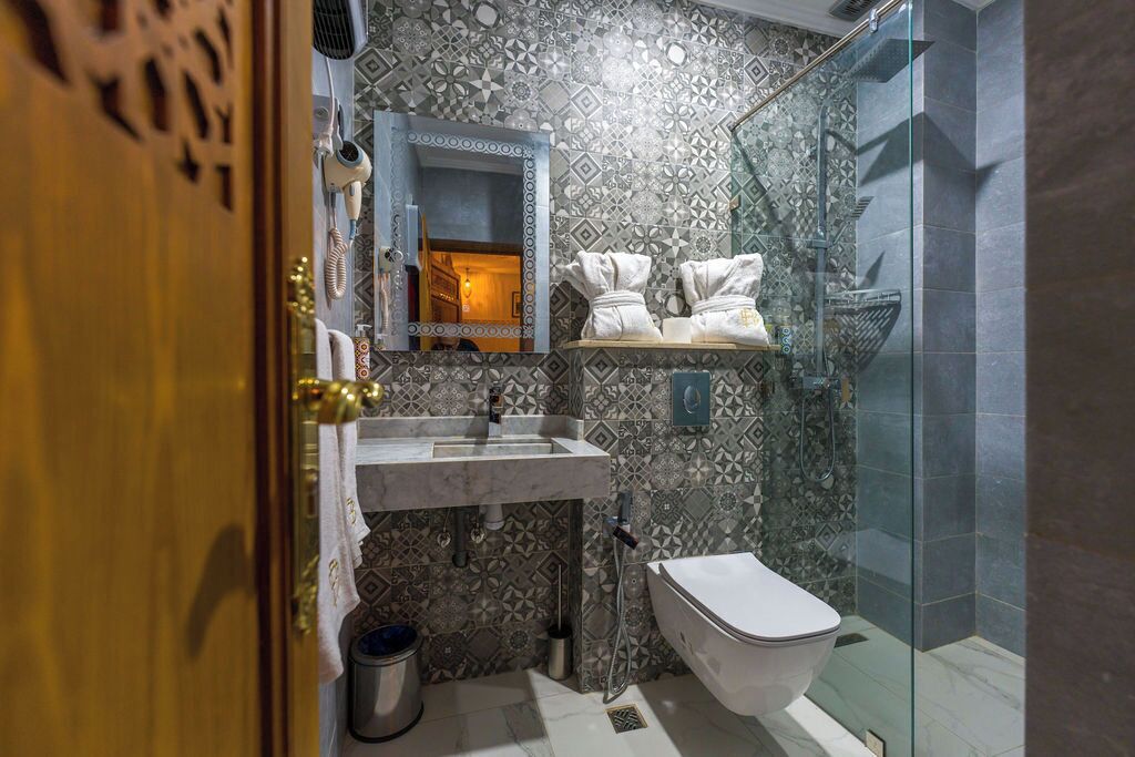 A bathroom with patterned tiles, a sink, a toilet, and a shower area.