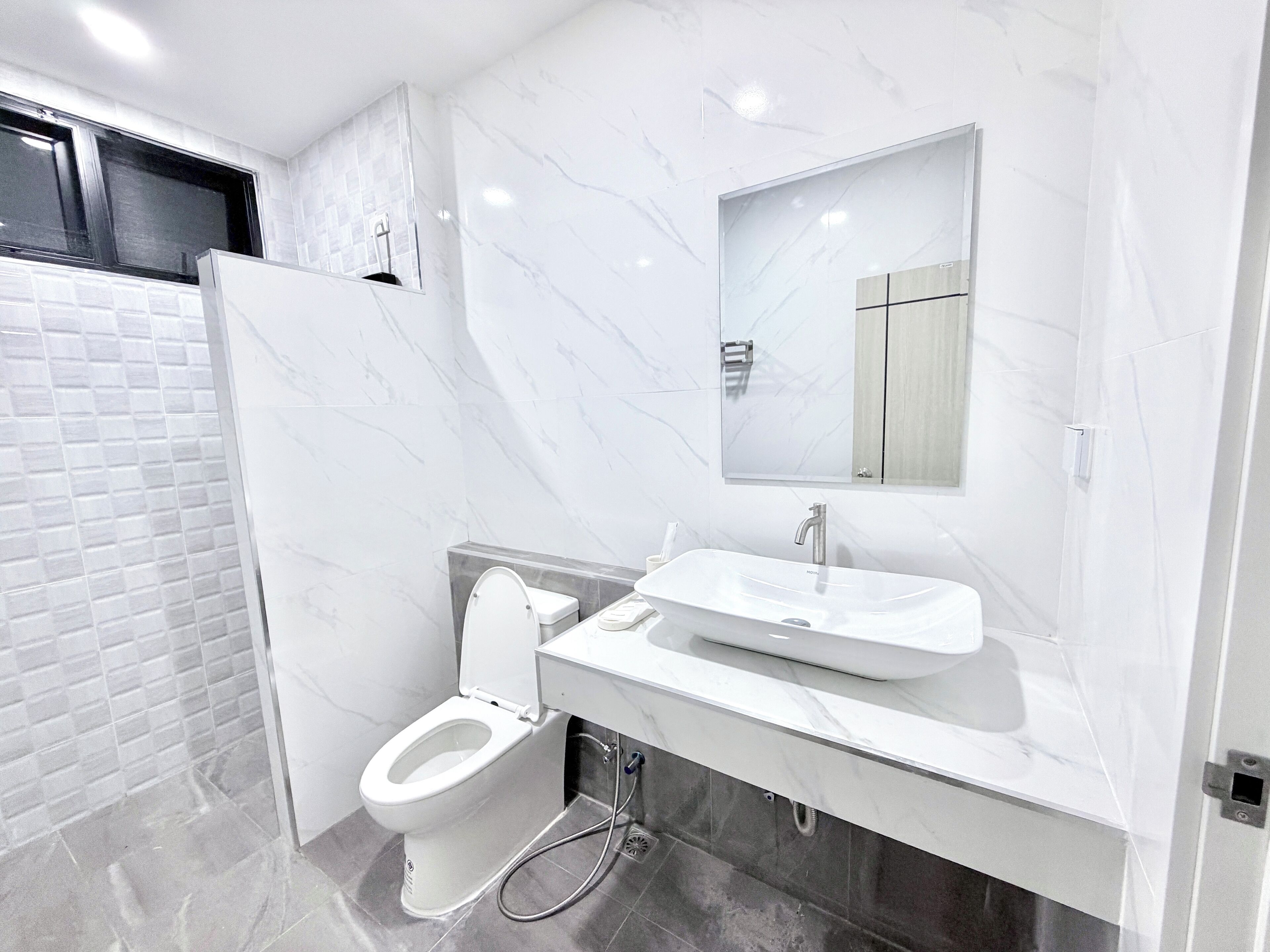 Un baño moderno con inodoro, lavamanos y espejo.