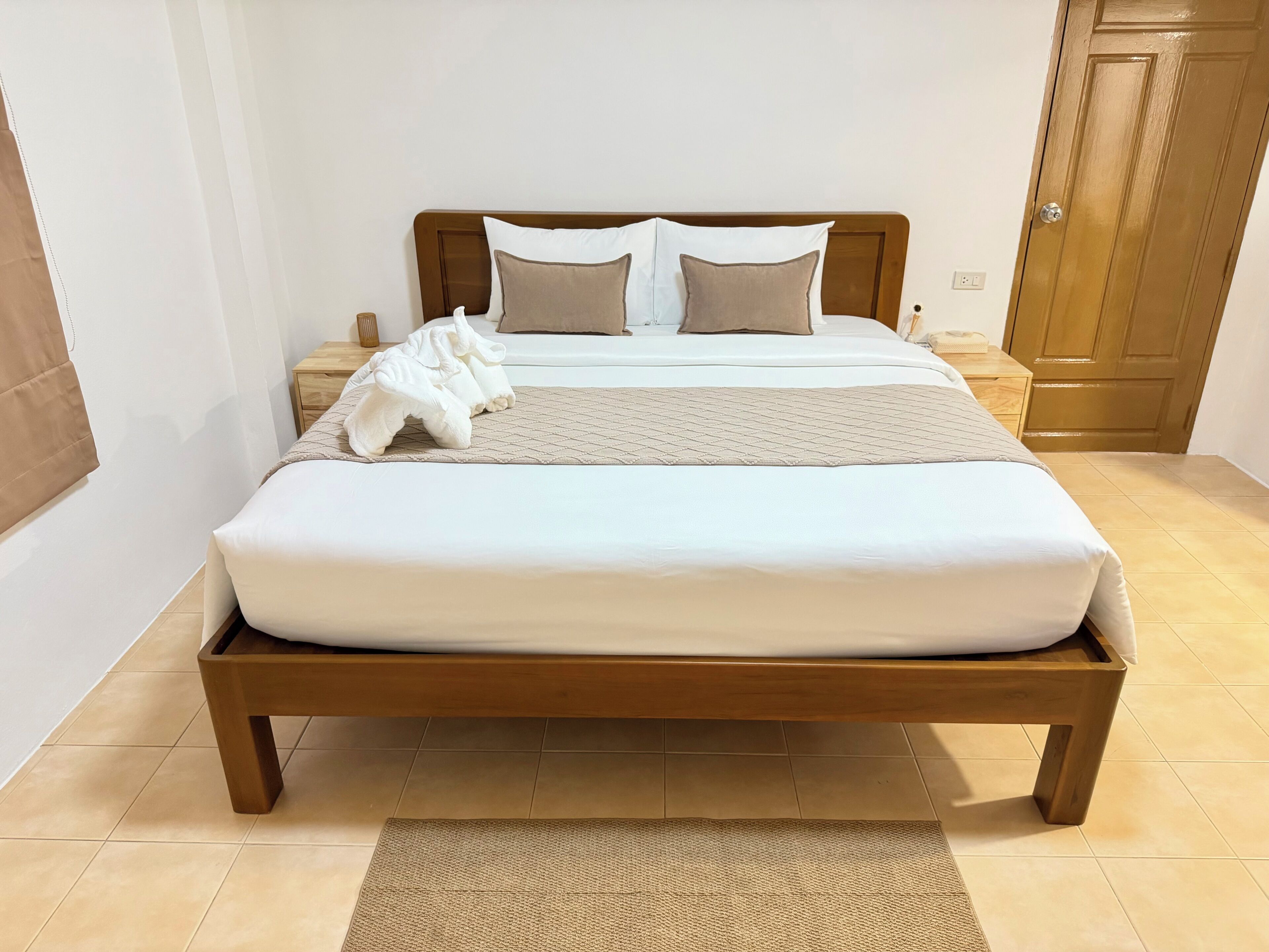 A neatly made bed with a wooden frame, a headboard, and a bedside table with a lamp.