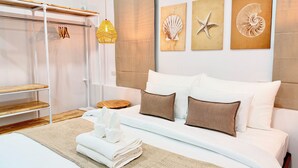 A neatly arranged bedroom with a bed, pillows, a bedside table, a hanging light, and wall art. - Labelle villa koh phangan (Ko Pha-ngan)