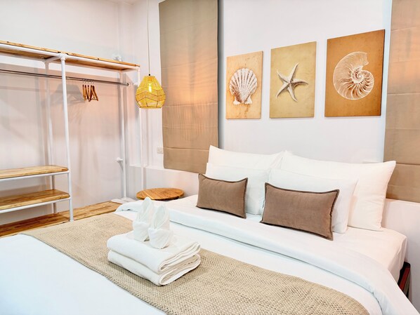 A neatly arranged bedroom with a bed, pillows, a bedside table, a hanging light, and wall art. - Labelle villa koh phangan (Ko Pha-ngan)