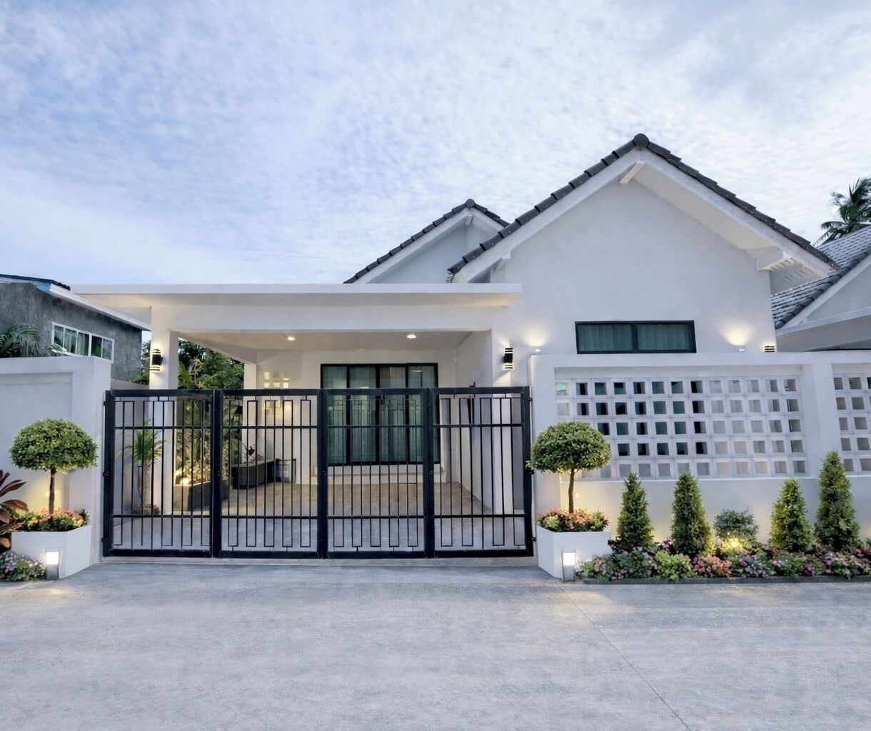 A modern house with a gated entrance, a covered porch, and a white fence with a lattice design.
