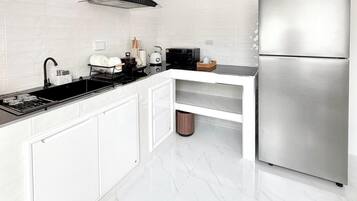 A modern kitchen with white cabinetry, a stainless steel refrigerator, a black induction cooktop, and a built-in oven.