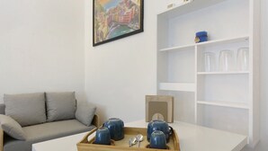 Una sala de estar moderna con un sofá, una mesita de centro, una bandeja con tazas y una cuchara, y una estantería.