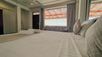 A hotel room with a large bed, a view of the outdoors, and a ceiling fan.