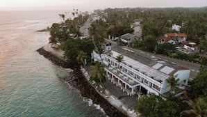 An aerial view of a coastal hotel with a beachfront patio, multiple balconies, and a view of the ocean. - Beach House Goviyapana (Matara Road, Goiyapana,)