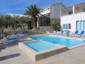 Ein Swimmingpool mit Liegestühlen, einer Palme und einer Steinmauer.