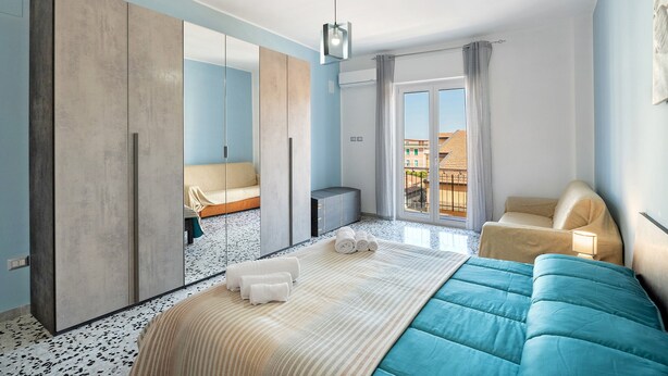 Une chambre d’hôtel moderne dotée d’un grand lit, d’une armoire, d’un coin salon et d’un balcon avec vue.