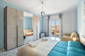 Een moderne hotelkamer met een groot bed, een kledingkast, een zithoek en een balkon met uitzicht.