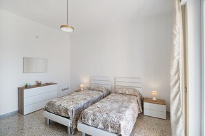 Een slaapkamer met twee bedden, een kaptafel, een nachtkastje, een lamp en een spiegel.