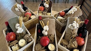 Un coin repas avec une table ronde entourée de chaises, chacune ayant un panier contenant une bouteille, une bougie et une grenade.