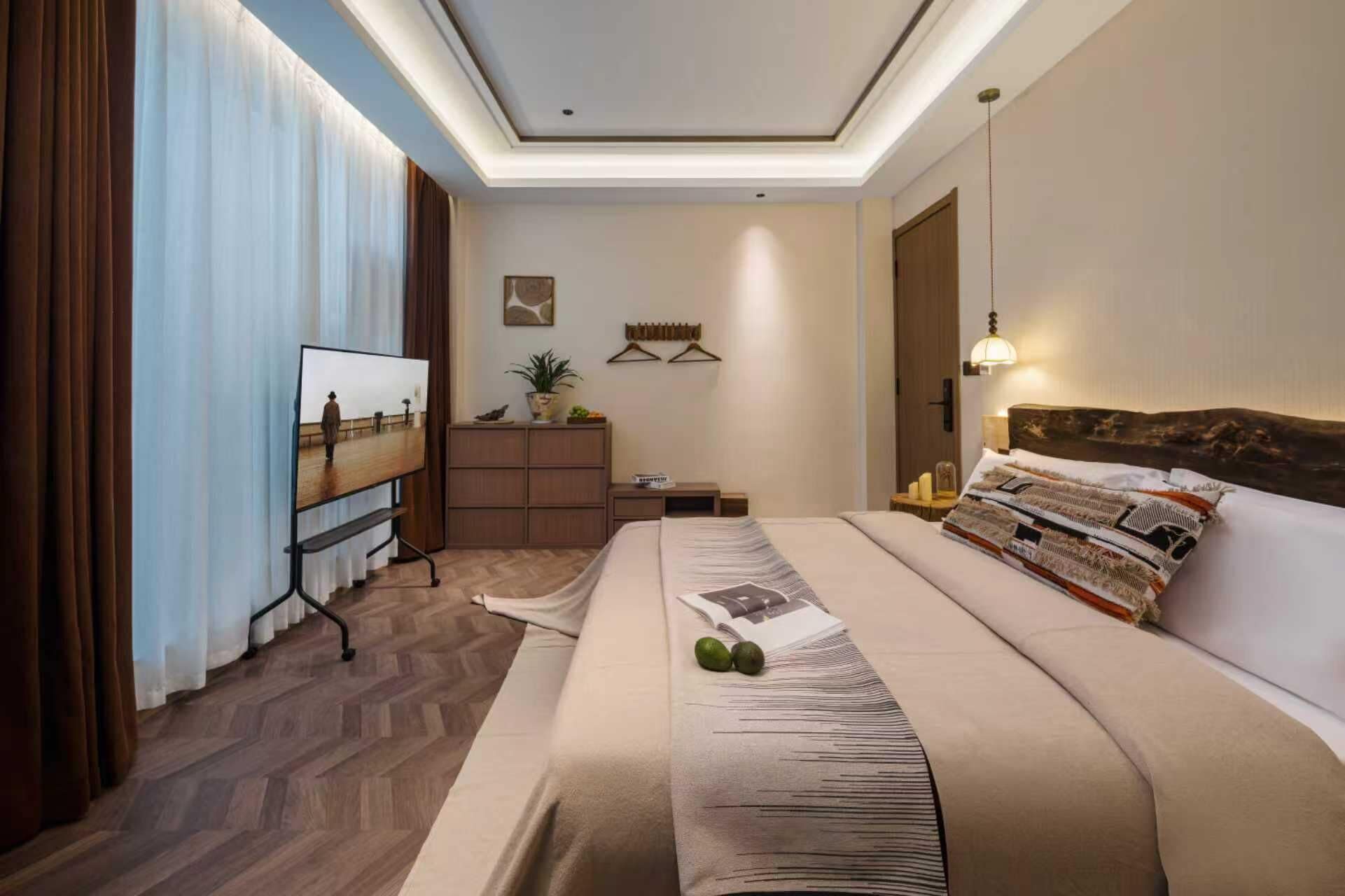Quarto de hotel com cama grande, televisão, escrivaninha e planta em vaso.