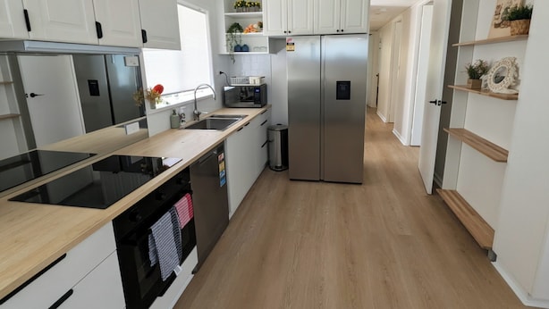A modern kitchen with stainless steel appliances, white cabinetry, and wooden flooring. - 3-bedroom peaceful house with backyard, EV charger (and free parking), and AC (Macquarie)