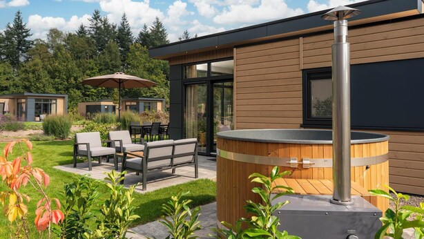 A modern outdoor patio with seating, a hot tub, and a wooden deck. - Enjoy a private hot tub and sauna, a cosy outdoor lounge with fireplace and a luxurious outdoor area at the Cannenburch Deluxe. (Lieren)