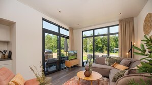 A modern living room with a sofa, a coffee table, and a television. - Enjoy a private hot tub and sauna, a cosy outdoor lounge with fireplace and a luxurious outdoor area at the Cannenburch Deluxe. (Lieren)