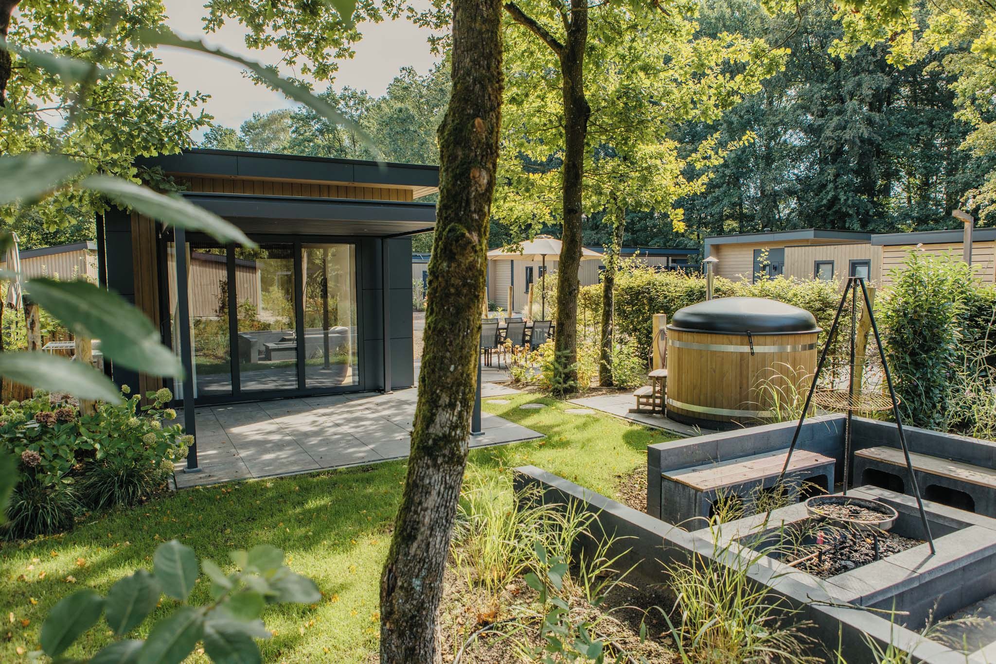 Un espacio exterior moderno con zona de estar cubierta, jacuzzi y jardín cuidado.