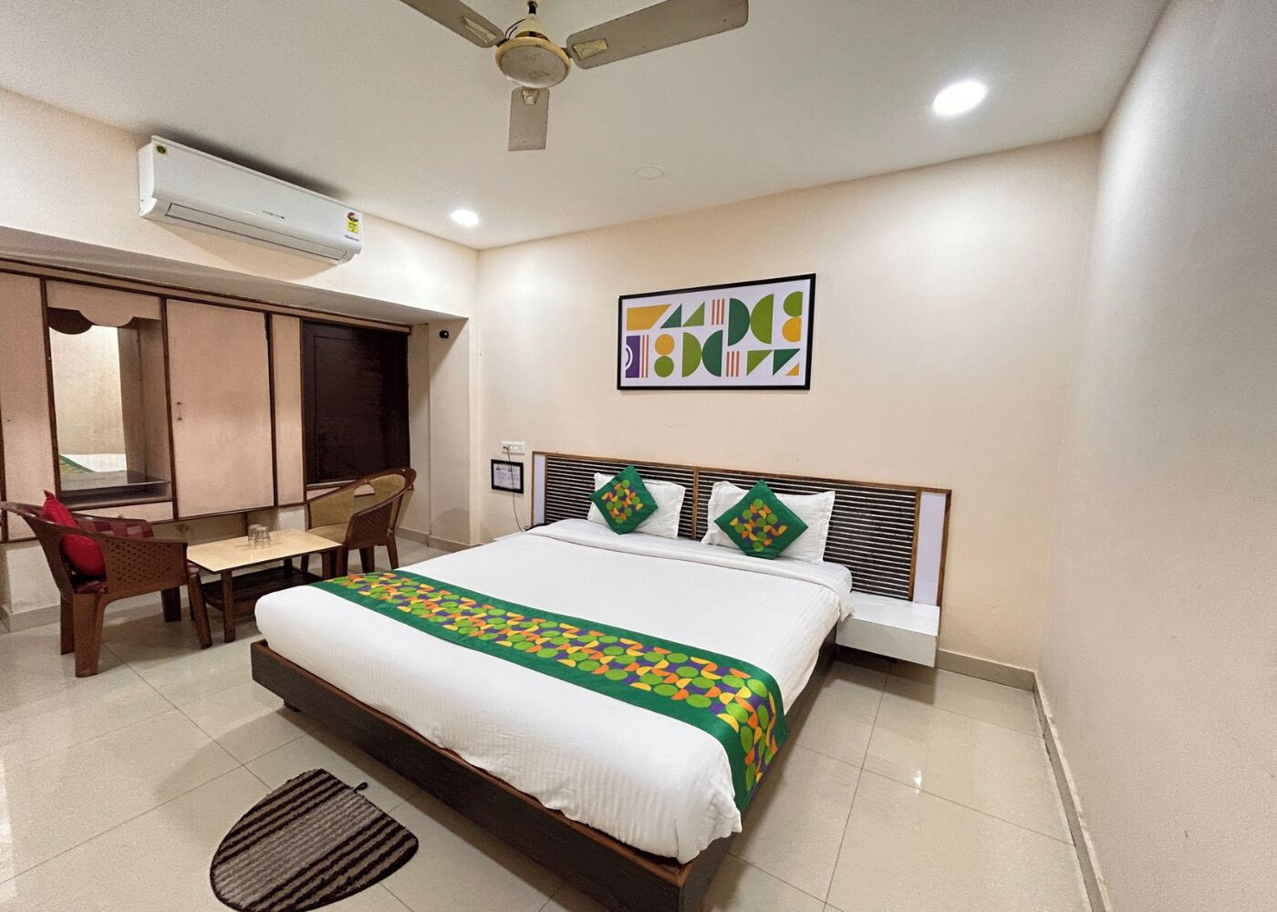 A hotel room with a bed, a desk, a chair, and a ceiling fan.