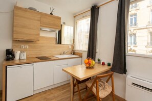 Une cuisine compacte dotée d’un plan de travail en bois, d’un évier et d’une table à manger sur laquelle se trouve un panier de fruits.