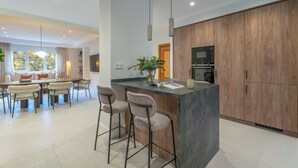 Una cucina moderna con isola centrale, sgabelli da bar, mobili in legno e una zona pranzo con tavolo e sedie.