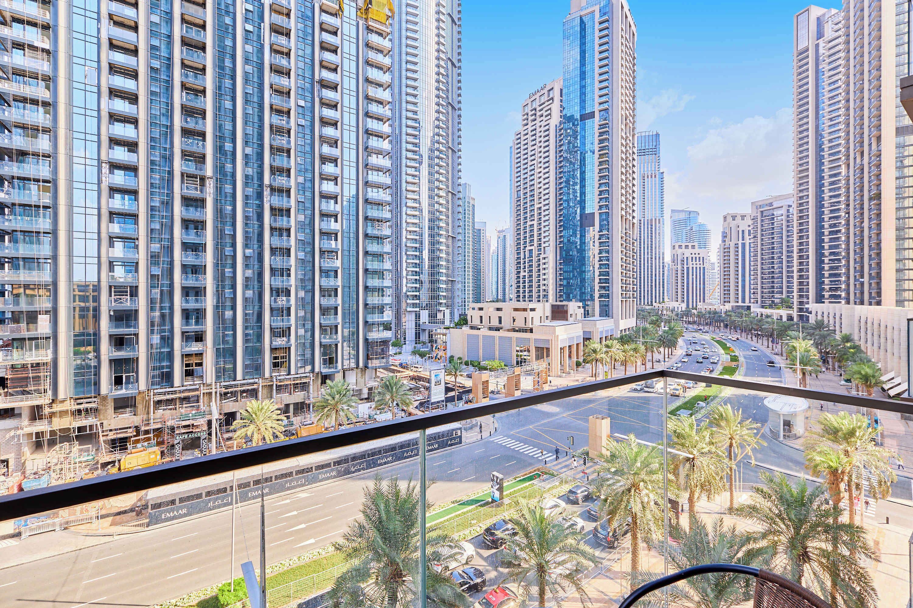 A high-rise building with multiple floors, large windows, and a view of a busy street with palm trees and cars.