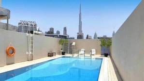 A rooftop swimming pool with a view of the Burj Khalifa. - Luxury 1BHK with Stunning Canal View Business Bay (Dubai)
