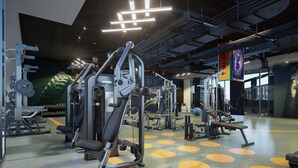 Une salle de sport équipée de divers appareils d’exercice, un mur orné de citations motivantes et un plafond avec des poutres apparentes et des luminaires.