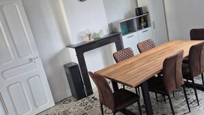 Ein Essbereich mit einem Holztisch, braunen Stühlen, einer schwarzen Pendelleuchte, einer weißen Tür und einem gemusterten Boden.