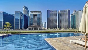 A swimming pool with a cityscape in the background. - Cityscape Comforts 2BR (Dubai)